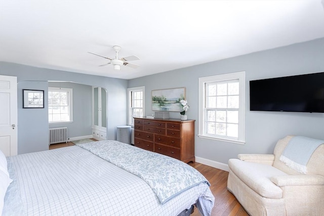 bedroom with multiple windows, radiator, hardwood / wood-style floors, and ceiling fan