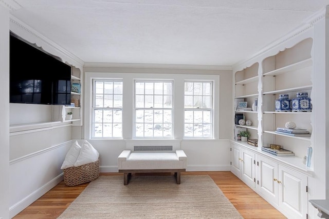 sitting room featuring crown molding, light hardwood / wood-style floors, and built in shelves