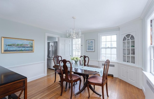 dining room with an inviting chandelier, ornamental molding, radiator heating unit, and light hardwood / wood-style floors