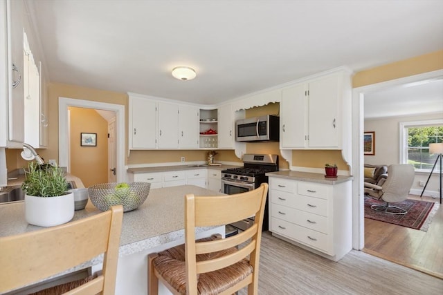 25 Piety Corner Rd, Waltham, MA 02451 - kitchen featuring appliances with stainless steel finishes, light wood finished floors, white cabinets, and open shelves