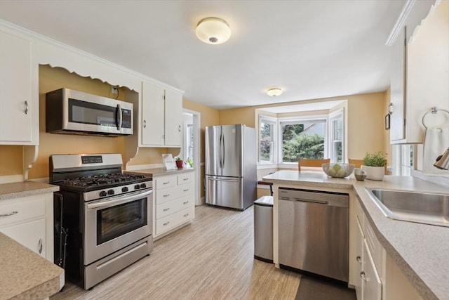 25 Piety Corner Rd, Waltham, MA 02451 - kitchen with stainless steel appliances, light countertops, a sink, white cabinets, and light wood-style floors