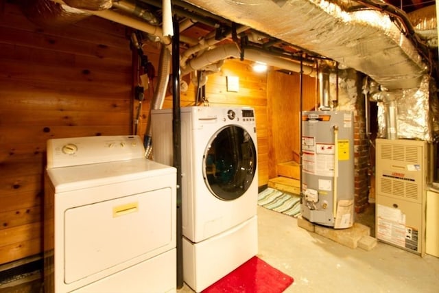 laundry area featuring washer and clothes dryer, wood walls, gas water heater, and heating unit