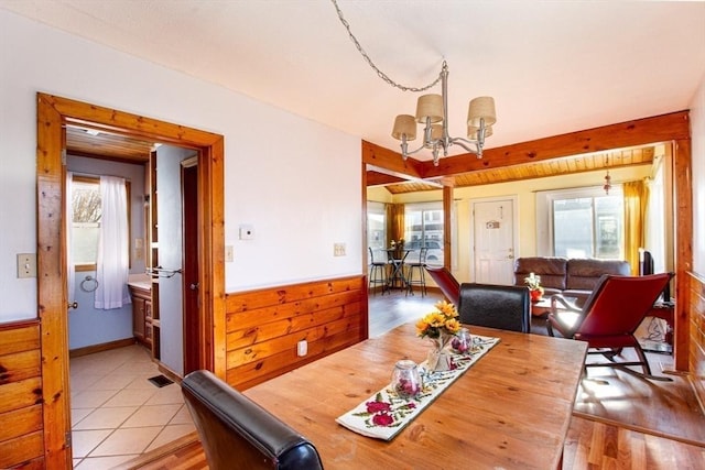 dining room featuring wooden walls and a notable chandelier