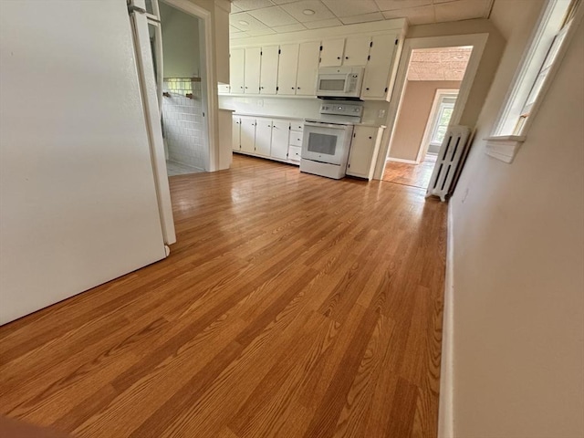 19 Chapel St, Shirley, MA 01464 - kitchen with white appliances, a paneled ceiling, white cabinets, light countertops, and light wood-style floors