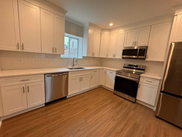 19 Chapel St, Shirley, MA 01464 - kitchen with stainless steel appliances, light wood-style floors, light countertops, white cabinets, and crown molding