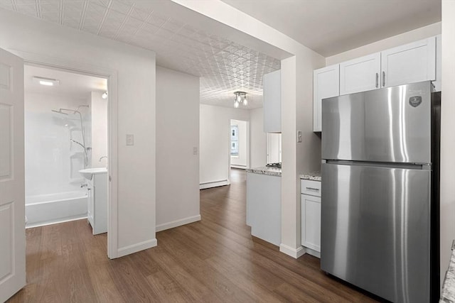 50 Howard St, Haverhill, MA 01830 - kitchen featuring freestanding refrigerator, dark wood-style flooring, white cabinets, and light stone counters
