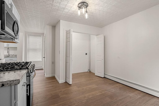50 Howard St, Haverhill, MA 01830 - kitchen featuring stainless steel appliances, a baseboard heating unit, light wood-type flooring, light countertops, and an ornate ceiling