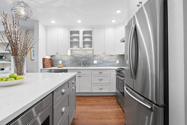 256 W Newton St Unit 1, Boston, MA 02116 - kitchen with stainless steel appliances, a sink, white cabinetry, glass insert cabinets, and decorative backsplash