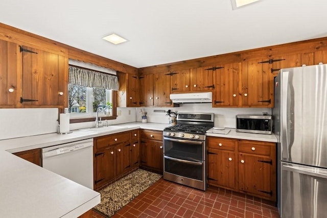 56 Fairwood Rd, Yarmouth, MA 02664 - kitchen with brick patterned floor, under cabinet range hood, stainless steel appliances, light countertops, and a sink