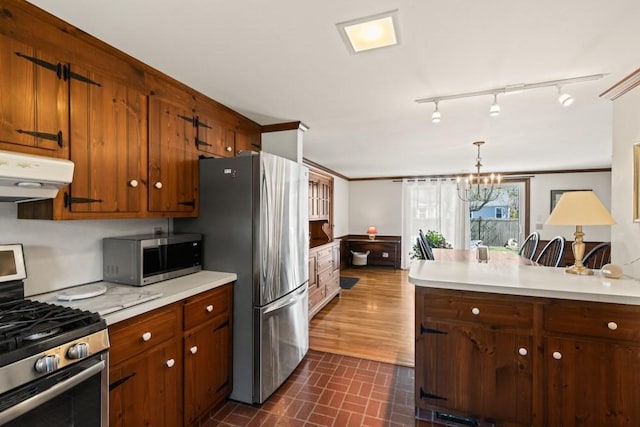 56 Fairwood Rd, Yarmouth, MA 02664 - kitchen with under cabinet range hood, an inviting chandelier, light countertops, track lighting, and stainless steel appliances