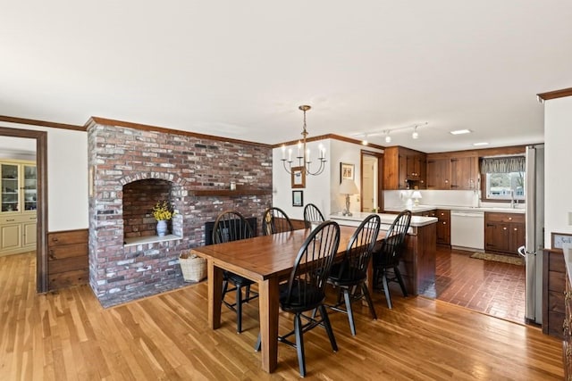 56 Fairwood Rd, Yarmouth, MA 02664 - dining room featuring an inviting chandelier, crown molding, a brick fireplace, and light wood-type flooring