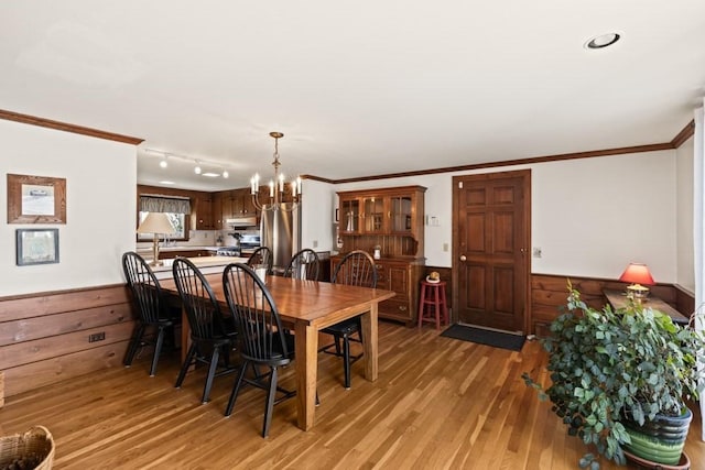 56 Fairwood Rd, Yarmouth, MA 02664 - dining space with light wood finished floors, a wainscoted wall, wood walls, crown molding, and a notable chandelier