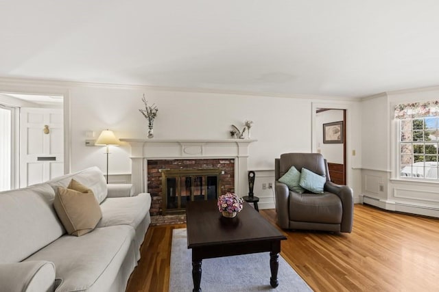 56 Fairwood Rd, Yarmouth, MA 02664 - living area with wood finished floors, crown molding, wainscoting, a brick fireplace, and baseboard heating