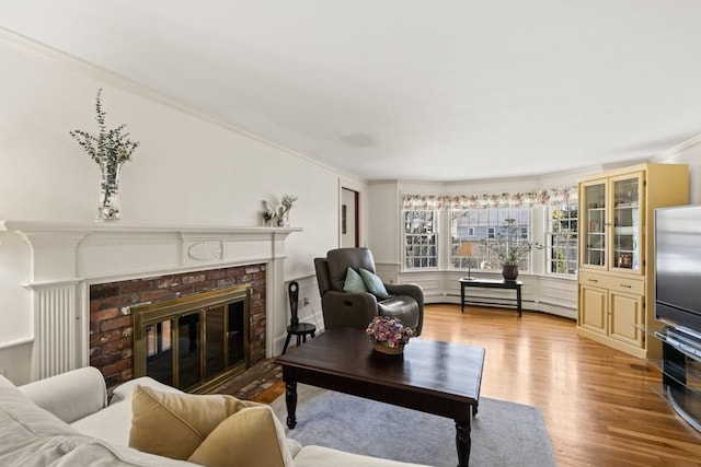 56 Fairwood Rd, Yarmouth, MA 02664 - living area featuring a baseboard heating unit, light wood-type flooring, a brick fireplace, and crown molding
