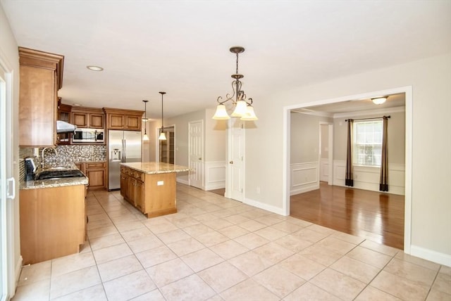 12 Kestrel Ln Unit 7, Westford, MA 01886 - kitchen with appliances with stainless steel finishes, light tile patterned floors, a center island, decorative backsplash, and light stone counters