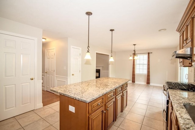 12 Kestrel Ln Unit 7, Westford, MA 01886 - kitchen with brown cabinetry, gas stove, light tile patterned flooring, under cabinet range hood, and hanging light fixtures