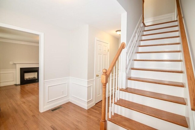 12 Kestrel Ln Unit 7, Westford, MA 01886 - staircase with wood finished floors, a wainscoted wall, a decorative wall, and a fireplace with flush hearth