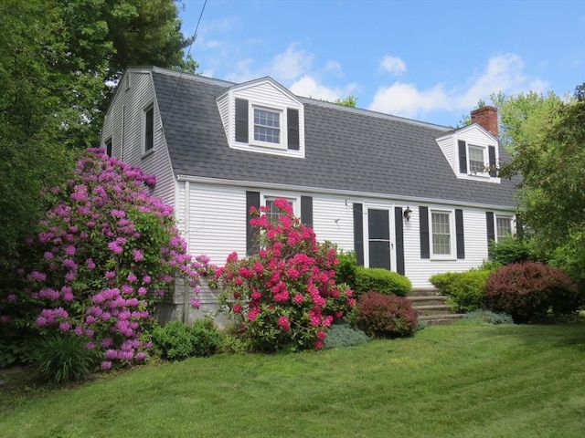 view of front of house with a shingled roof, a chimney, a gambrel roof, and a front yard