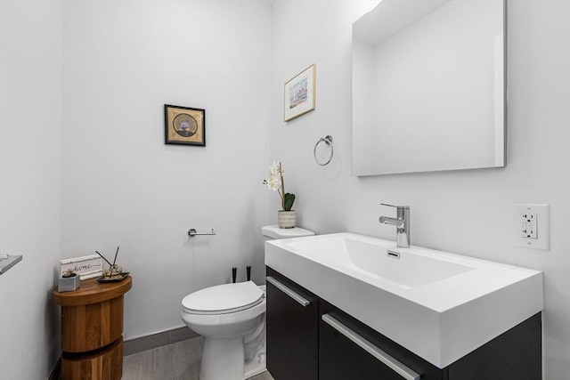 bathroom featuring toilet, vanity, and wood finished floors