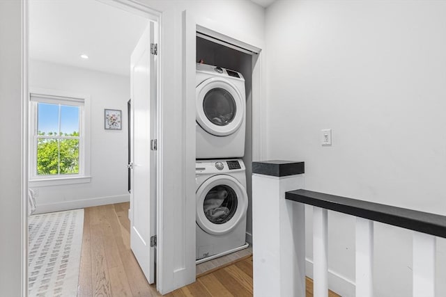 laundry area featuring stacked washer / dryer, light wood finished floors, baseboards, and recessed lighting