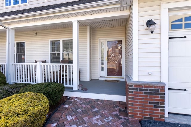 doorway to property featuring covered porch and a garage