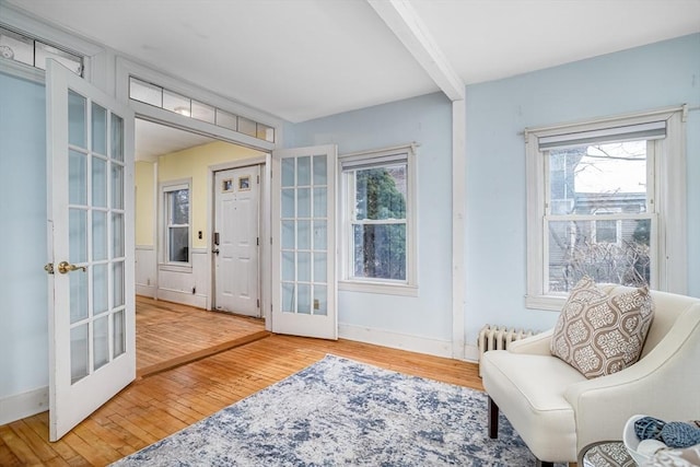 living area with wood-type flooring, radiator heating unit, and french doors