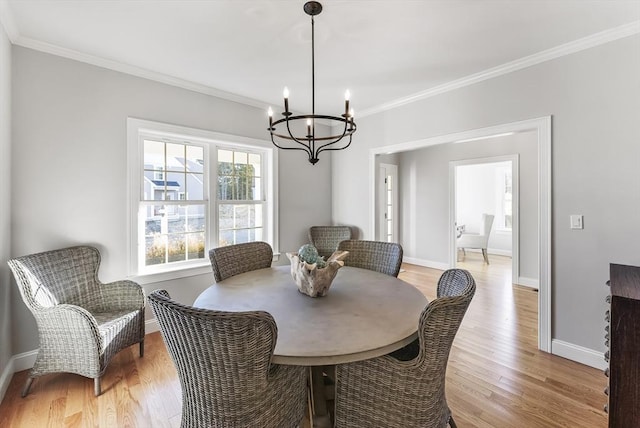 dining room featuring a notable chandelier, light wood-style floors, baseboards, and ornamental molding