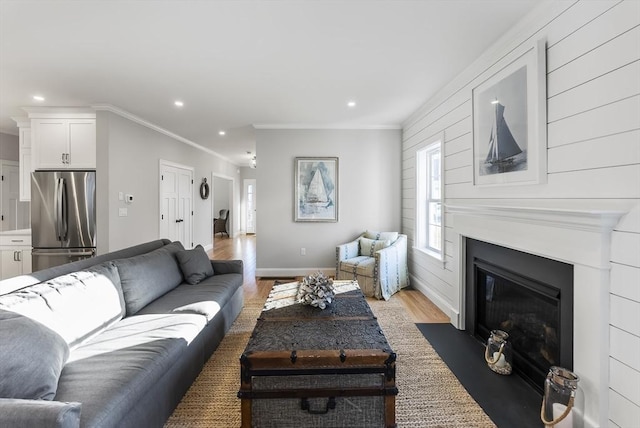 living room with light wood finished floors, baseboards, a fireplace with flush hearth, ornamental molding, and recessed lighting