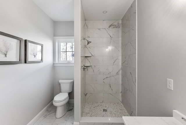 bathroom featuring baseboards, toilet, marble finish floor, and a tile shower