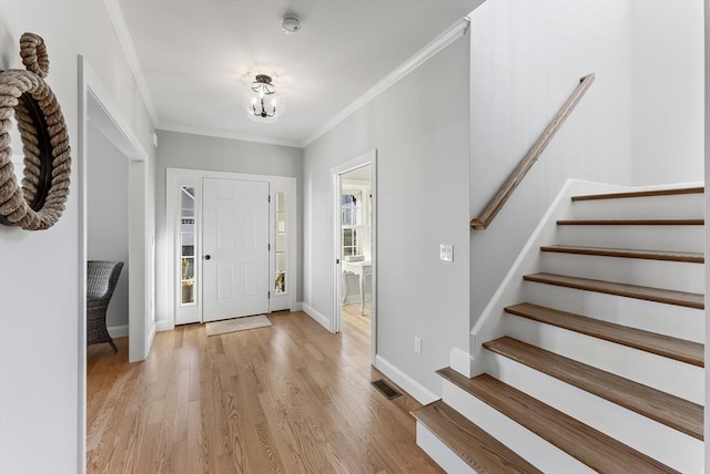 entryway with visible vents, crown molding, baseboards, stairway, and light wood-style flooring
