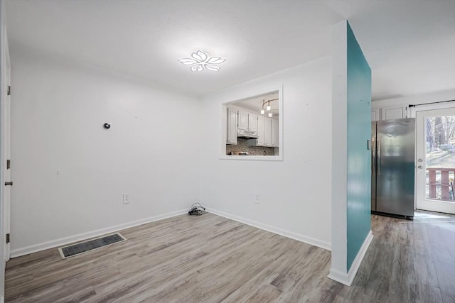 laundry area with visible vents, baseboards, and wood finished floors