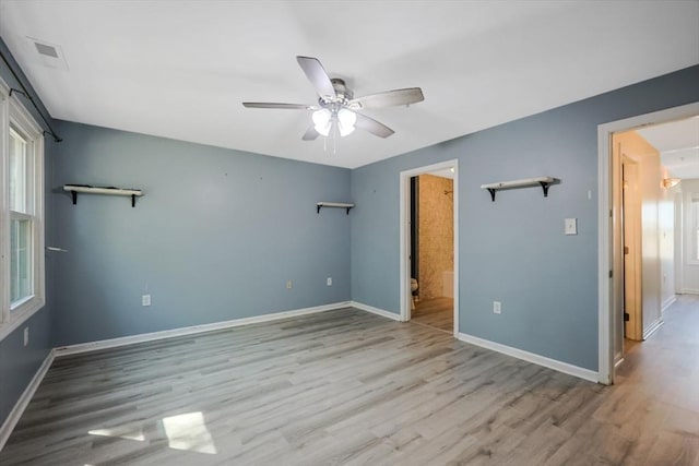 unfurnished bedroom with ceiling fan, ensuite bath, baseboards, wood finished floors, and visible vents