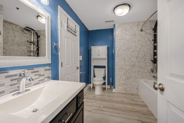 bathroom with visible vents, vanity, wood finished floors, toilet, and backsplash