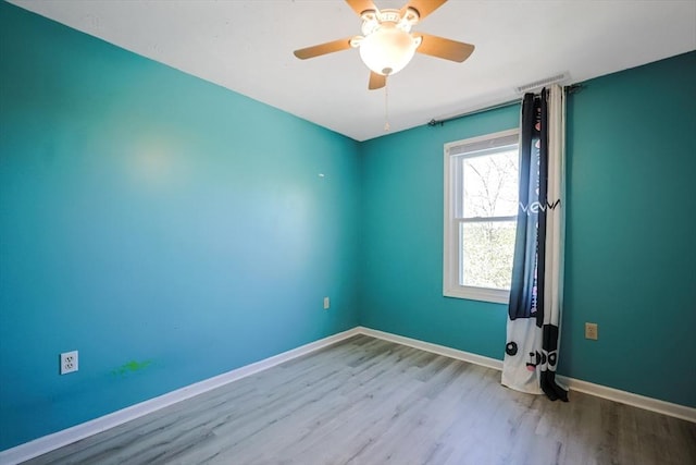 empty room with baseboards, ceiling fan, wood finished floors, and visible vents