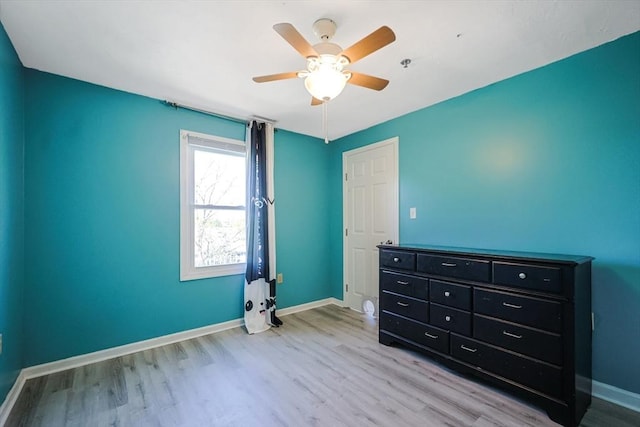 unfurnished bedroom with a ceiling fan, baseboards, and light wood-type flooring