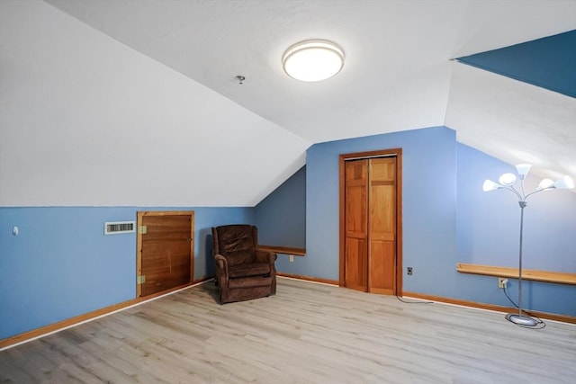 unfurnished room with visible vents, baseboards, lofted ceiling, and wood finished floors