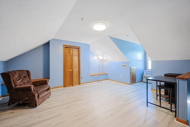 additional living space featuring baseboards, visible vents, lofted ceiling, and light wood-type flooring