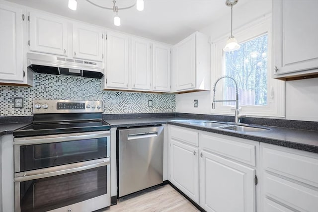 kitchen with under cabinet range hood, stainless steel appliances, white cabinets, and a sink