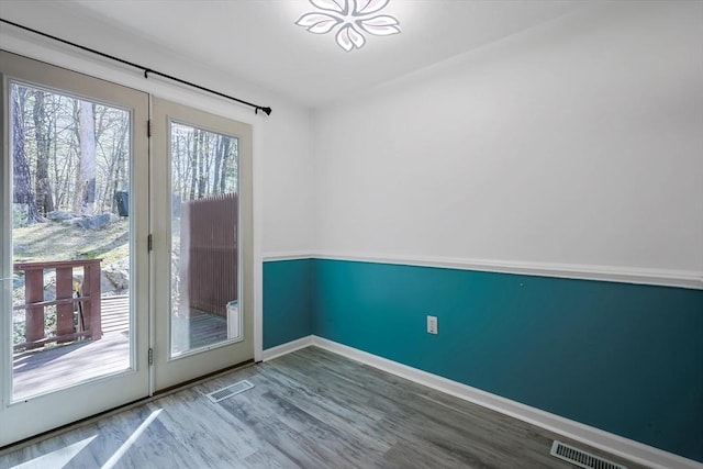 interior space with baseboards, visible vents, and wood finished floors