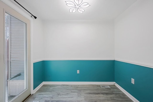 empty room with baseboards, wood finished floors, and visible vents