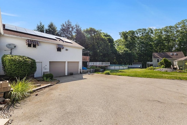 225 W Main St, Dudley, MA 01571 - view of property exterior with an attached garage, driveway, roof mounted solar panels, and an outdoor pool