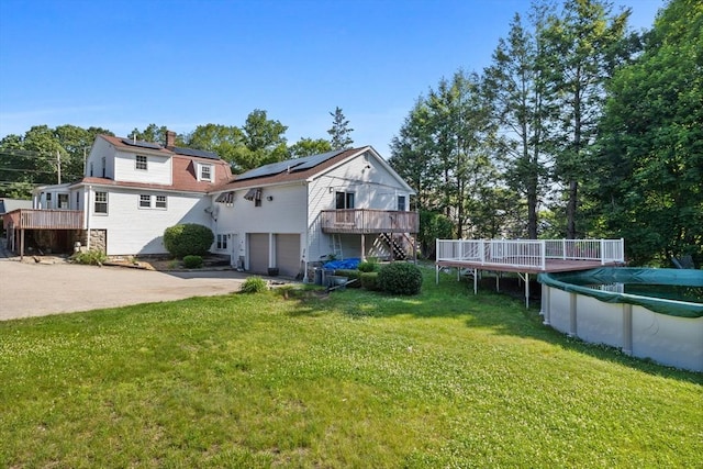 225 W Main St, Dudley, MA 01571 - back of property with stairs, a deck, a garage, driveway, and roof mounted solar panels