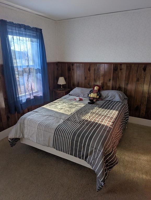 bedroom with carpet floors and wood walls