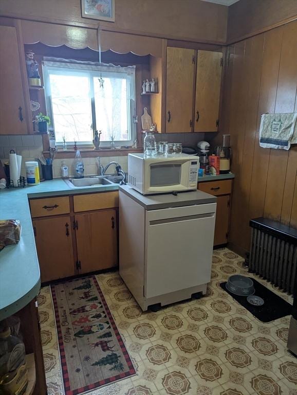 kitchen featuring fridge, wooden walls, and sink