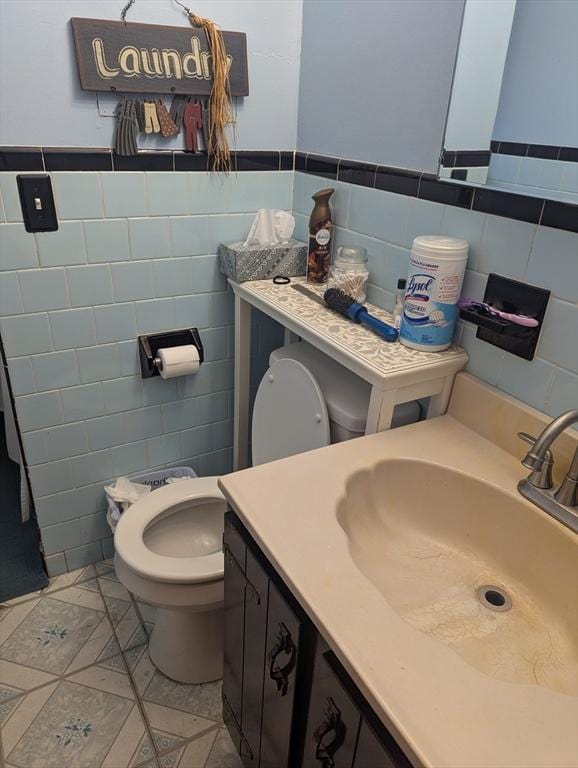 bathroom featuring vanity, tile walls, tile patterned floors, and toilet