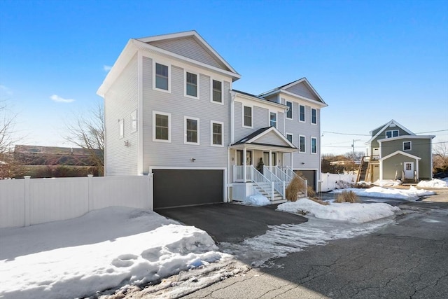 view of front of house with a garage, fence, and aphalt driveway