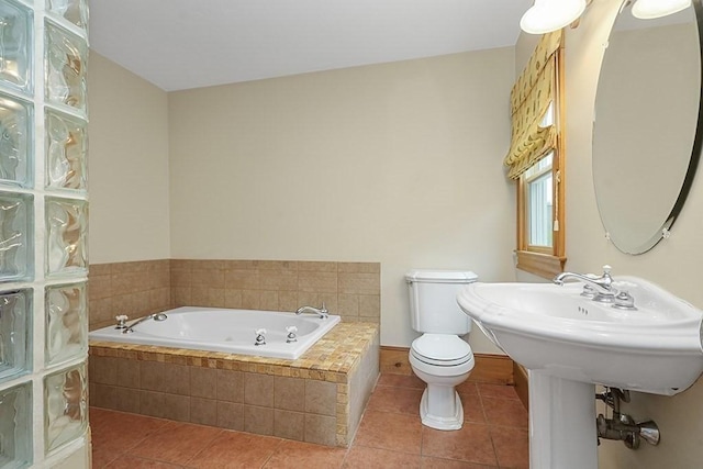full bathroom with toilet, a tub with jets, tile patterned flooring, and baseboards