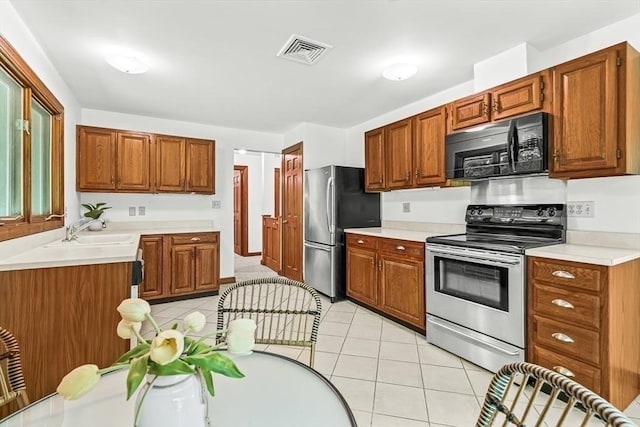 22 Grove Pl Unit 4, Winchester, MA 01890 - kitchen with appliances with stainless steel finishes, a sink, light tile patterned floors, light countertops, and brown cabinetry