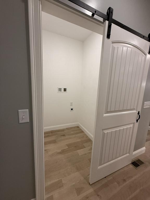 24 Cooper Rd, Webster, MA 01570 - washroom featuring hookup for a washing machine, light wood-style flooring, a barn door, and hookup for an electric dryer