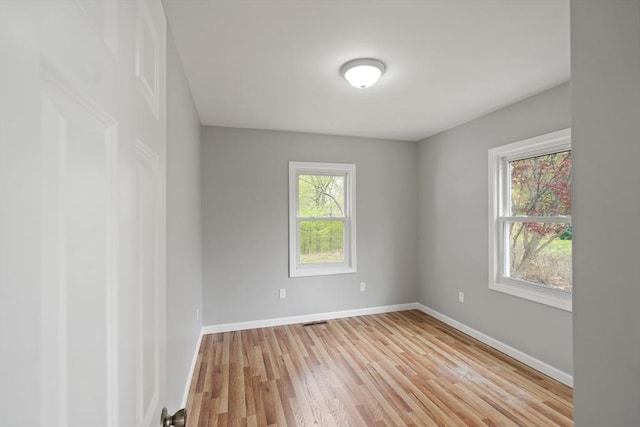 spare room featuring light wood-style floors, baseboards, and visible vents